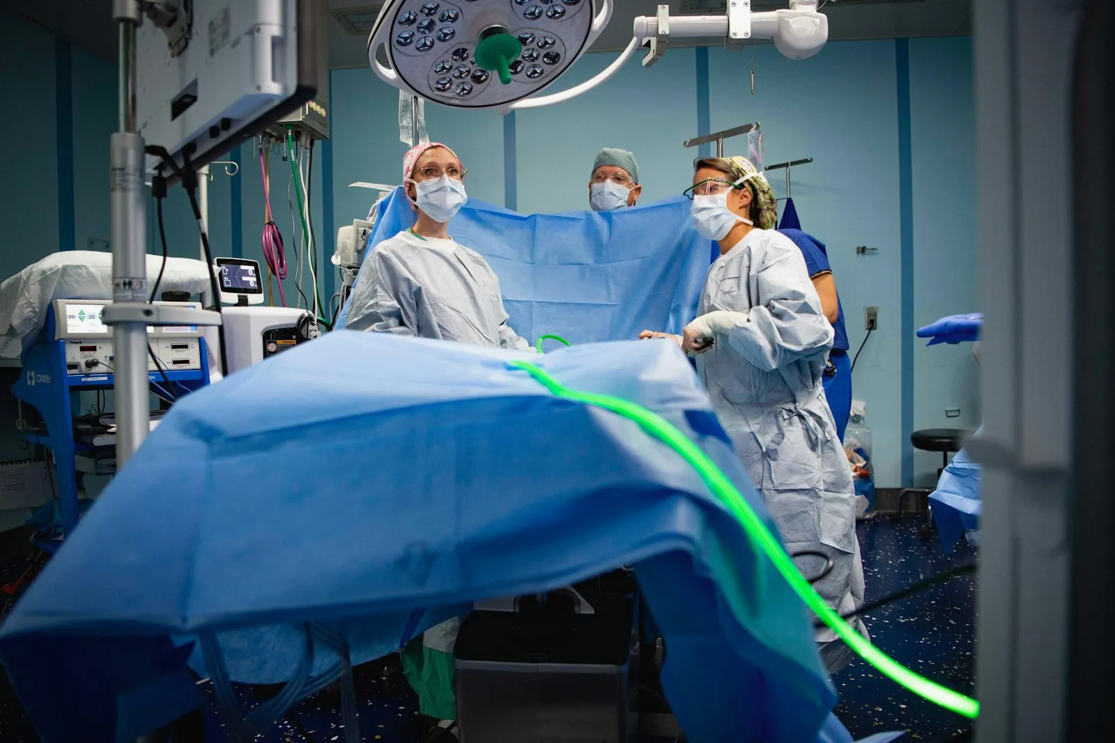 Echipă medicală în halate sterile, într-o sală de operație cu câmp steril